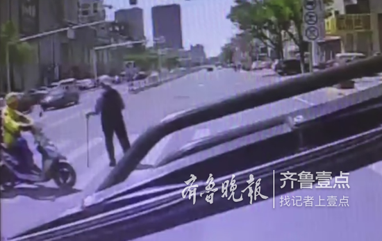 外卖小哥见老人行动不便,将摩托车停在斑马线一侧,挡住即将驶来的车流。