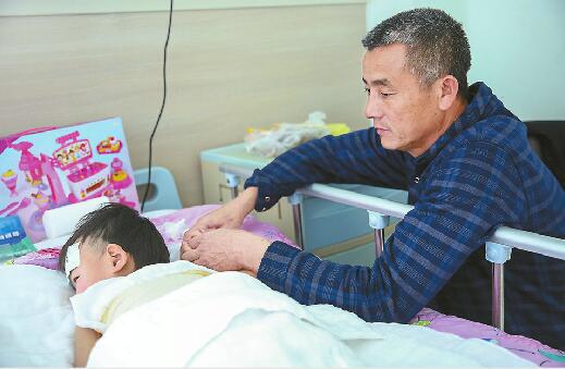 22日，山东省立医院，爷爷在病床前照顾小满。 记者刘玉乐 摄