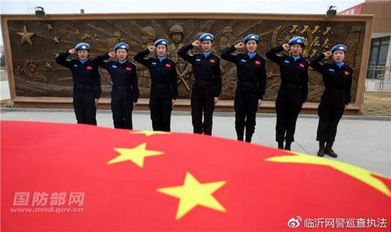 7名维和女队员在维和警队浮雕前面向国旗庄严宣誓