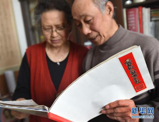 青岛退休教师张伟源和老伴在家中翻看《工资收入凭证汇集》(3月8日摄)。