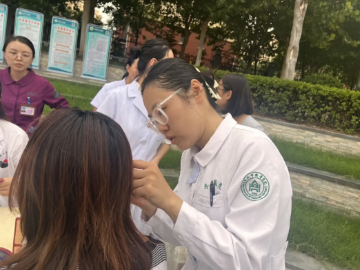 山东大学齐鲁医院中医科护师徐琳琳现场为群众进行耳穴压豆治疗