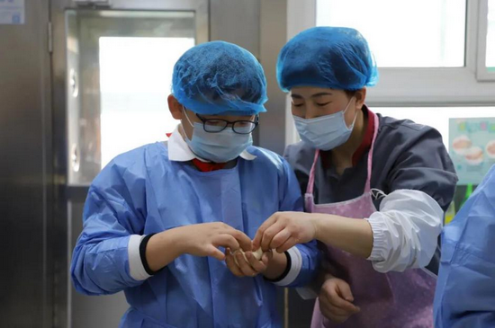 学生们在餐厅老师的帮助下尝试包包子