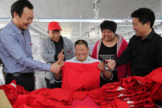 臨沭縣青云鎮(zhèn)王莊村智障青年馬兵兵首次嘗試檢查衣服釘扣工作