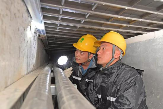 ▲气象局发布暴雨红色预警,国网济宁曲阜供电公司颜鑫和李亚凯屈膝在电缆沟进行检查,保障电网安全稳定运行。