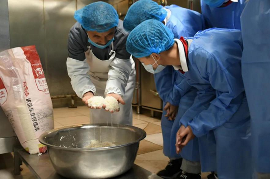 餐厅老师向学生们介绍淘米流程