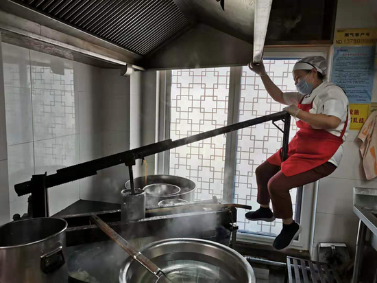 厨师正用和乐床子将面团压成面条