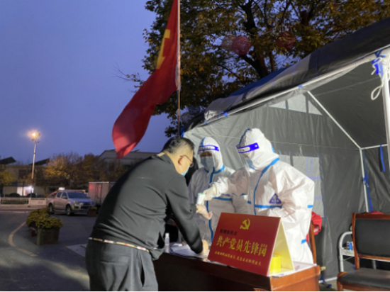 (在五莲县逸城山景小区门口,疫情防控党员先锋岗工作人员对返回小区的居民进行体温检测登记)