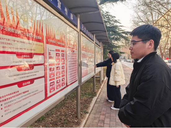 宣传栏前，青年学生认真阅读四中全会图文报道