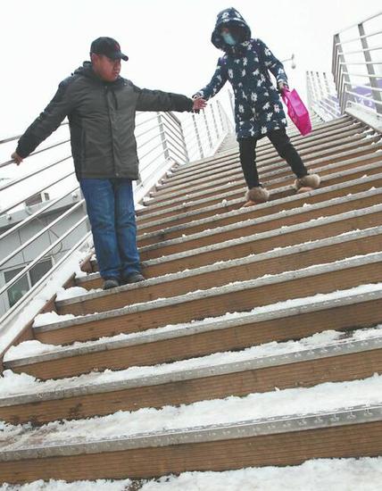 25日，两名市民小心翼翼地从省实验中学的过街天桥上走下。记者张勇 摄