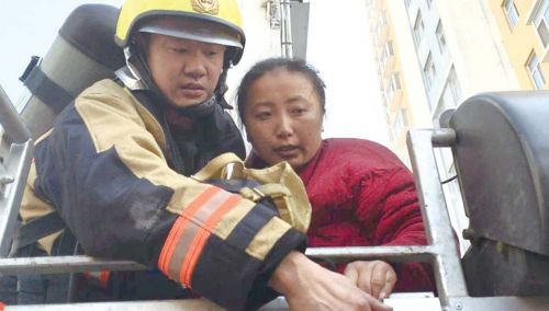 梁佃军救下一名被困者，通过登高消防车将她送下来。消防供图