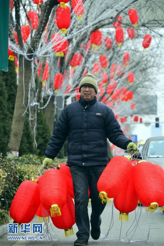 1月30日，在山东省聊城市东昌东路，工作人员在路边悬挂红灯笼。春节临近，人们开始加紧准备年货，各地张灯结彩，到处洋溢着节日的气息。 新华社发（赵玉国）