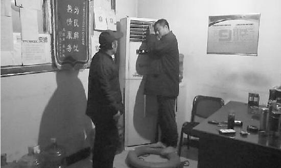 　男子在保安值班室，抱着空调取暖。视频截图