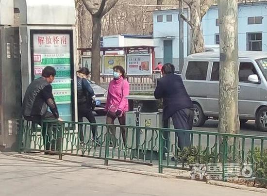 自稱是來自菏澤沒要到工錢的三名男子在公交站等車(圖中兩名男子背影)