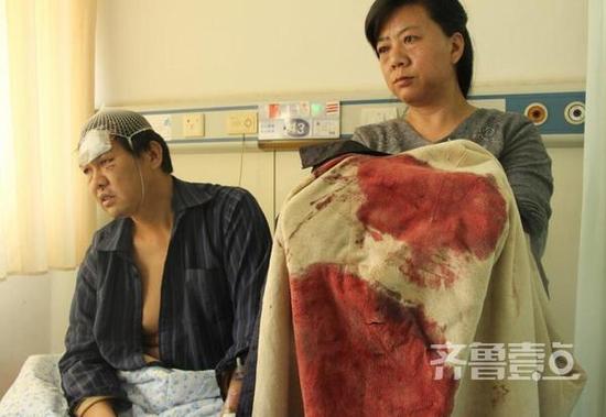 李立民(左)受伤时穿的衬衣上染满了鲜血,上面的刀口清晰可见。（齐鲁壹点记者 杜雅楠 摄）