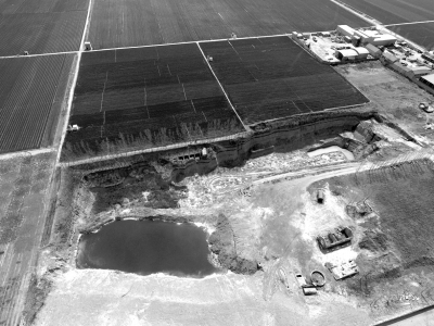 无人机拍摄的照片显示，巨大的污水坑紧邻耕地。