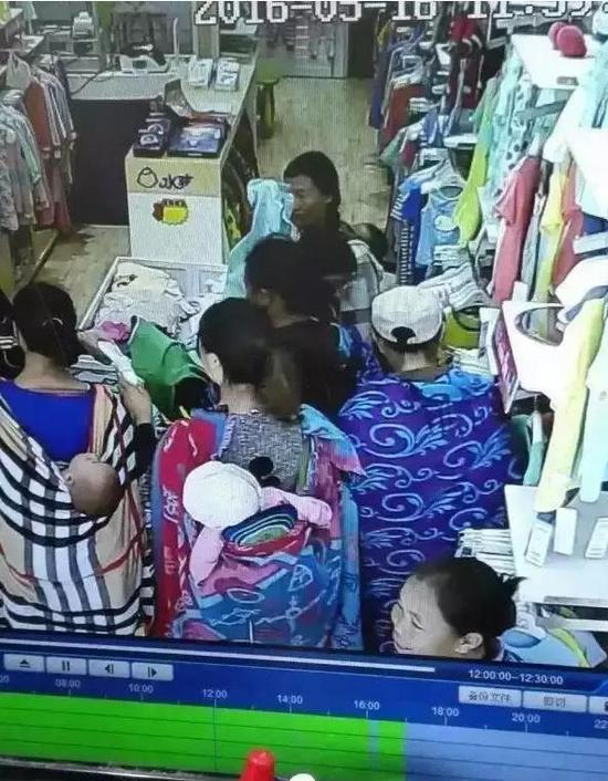 图为位于滕州一家童装店的监控视频截图，几名妇女背着孩子走进店中。