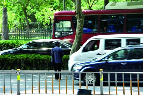 在经十路历山路路口，一名乞讨者在车流中穿梭