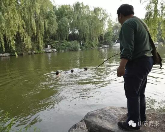 一位热心的市民正拿着一根木棍打算接应下水救人的好心人 市民 单东卫 摄