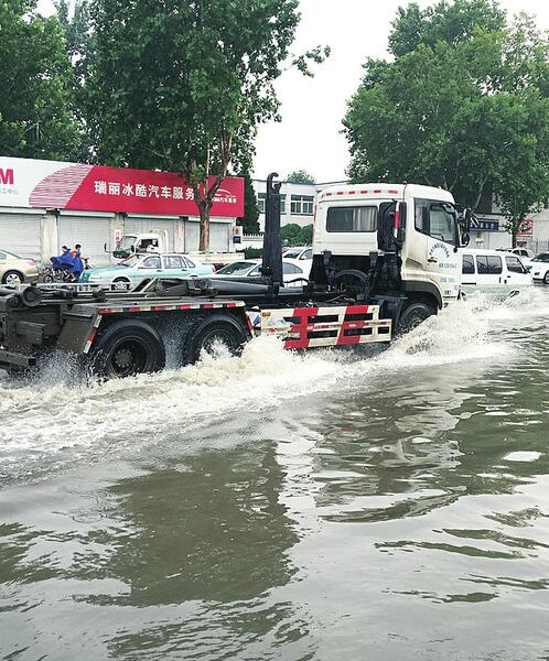 車輛冒雨在煙臺路東段積水中行進(jìn)。 (呂傳泉 攝)