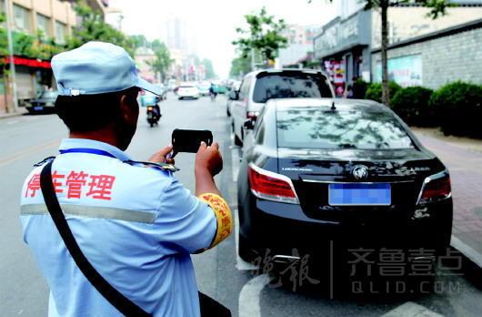 在濟南市區,一位停車管理員對停放車輛拍照取證。王鑫攝