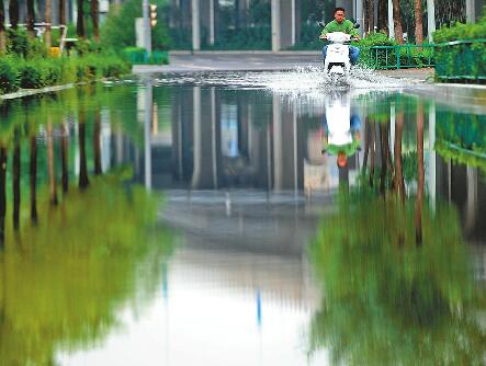 15日14時,持續十多個小時的降雨告一段落。在匡山立交橋西側,約百米的道路因排水不暢出現大片積水,最深處約10厘米,望去似一條小河。 記者王鋒 攝