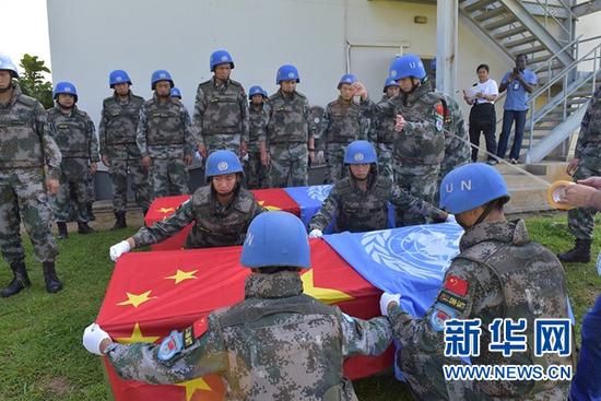7月15日,南蘇丹首都朱巴,中國維和步兵營官兵為犧牲戰士的靈柩覆蓋五星紅旗和聯合國旗。(新華網)