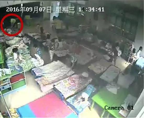 監控顯示一名身著黃色T恤的女老師走到男童跟前。