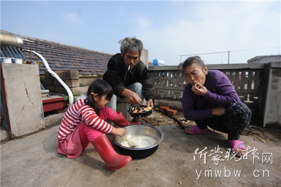 紅紅一家三口在平房頂上吃午飯，午飯是蒸的米飯和三天前好心人給的漢堡。