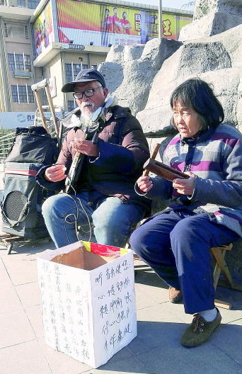 紀興軍與妻子在趵突泉北門的街頭附近彈琴賣藝。記者程凌潤 攝