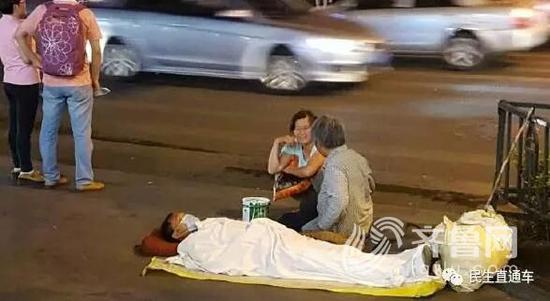 这位男子躺在地上装病人,老太太跪在那里要钱。
