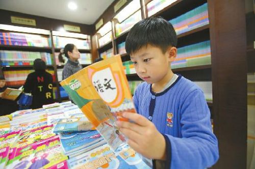 2月11日,在山东书城,小学一年级新版教科书已经上架销售,小学生顺顺在书店内尝鲜阅读。记者黄中明 摄