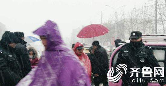 21日下午，菏泽定陶北关小学一中门口交通一时拥堵。特警冒着雪花站在街头维持学校门口秩序。（闪电新闻发 云淡风轻 摄）