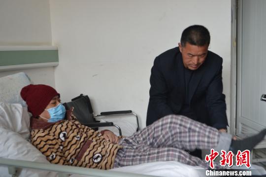 2月28日，在江西省鹰潭市人民医院病房内，现年50岁的邵新运正慢慢将亲家公吉书华扶上病床。　吴鹏泉　摄