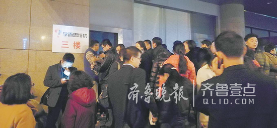 在學而思組織的一次模擬考試中,數以千計的家長晚上聚集在濟南金龍大廈狹窄的出口處,等著接孩子回家。(資料片)