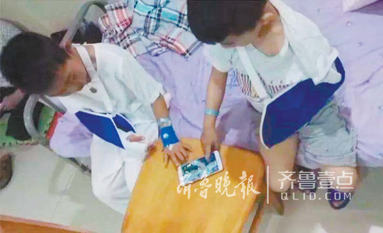 某医院中的两孩子因为手臂受伤，合作打《王者荣耀》。(资料片)