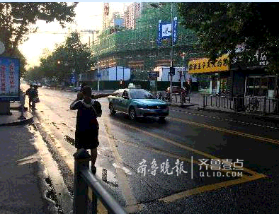 8日早晨五點半左右，花園路上，一輛開著空車燈的出租車從市民眼前駛過。齊魯晚報·齊魯壹點 記者劉飛躍攝