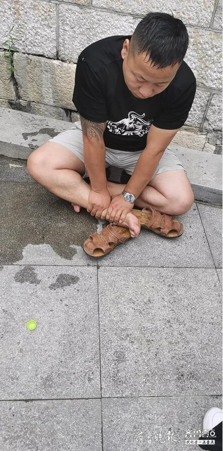 上岸后的刘光坦捂着自己受伤的脚踝