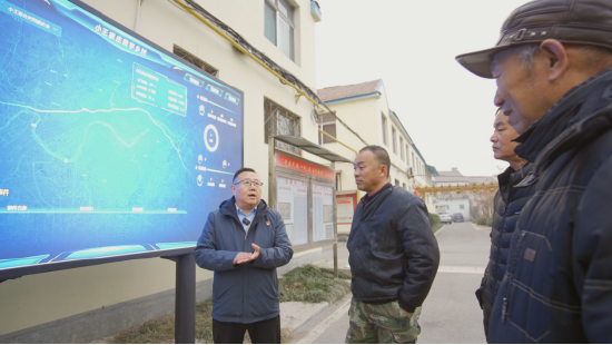 图为牛继林为村民讲解智慧大屏的功用