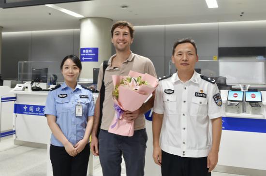 图说:上海机场边检站民警为卫星厅首位入境中转旅客送上鲜花。魏文亨 摄