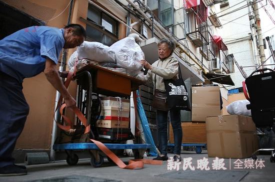 图说:家具和行李都搬到了楼下,杨建民扶着缝纫机看工人固定