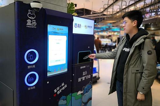 消费者将塑料杯盖投入智能回收机