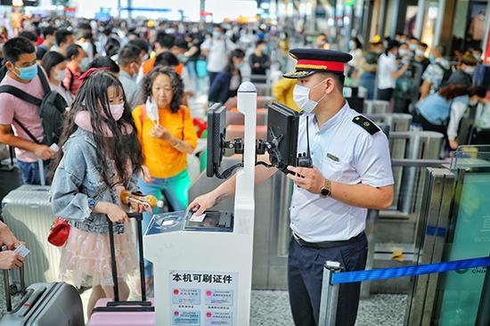 虹桥站检票口客运人员引导旅客使用电子客票。