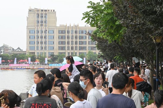 2026年6月19日，泗泾塘边的小区步道挤满了人，没有抢到观赛预约到观众聚集在这里，观看龙舟比赛。澎湃新闻记者 吴栋 图