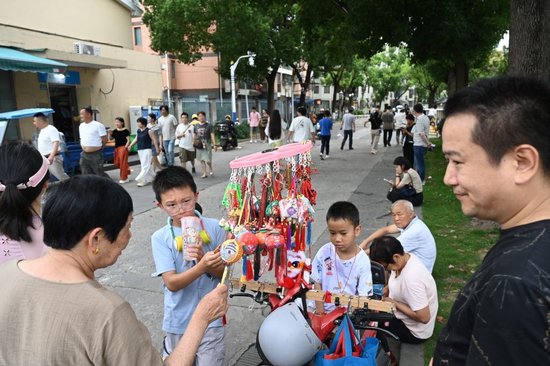 2026年6月19日，可以观看龙舟赛的小区吸引了很多游客，商贩在小区门口摆摊卖起了香囊和小饰物。澎湃新闻记者 吴栋 图