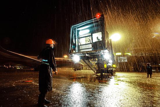 入汛后,机场保障人员在雨中操作登机桥。