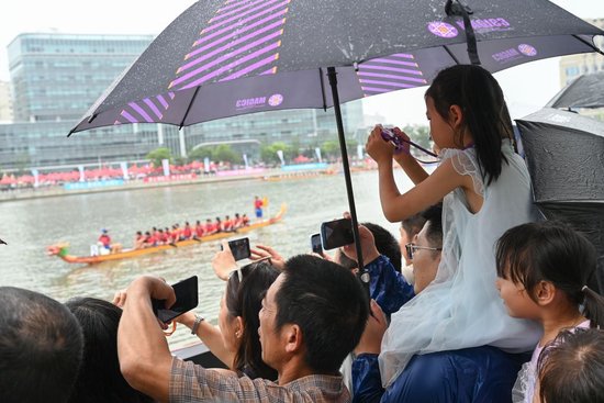 2026年6月19日，很多孩子被龙舟赛吸引，他们往往会被爸爸妈妈抱着托着举高高，图中的女孩坐在爸爸脖子上，方便观赛。澎湃新闻记者 吴栋 图