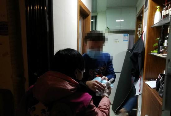 社区工作人员前往武汉返沪人员家中，送上口罩和消毒液。