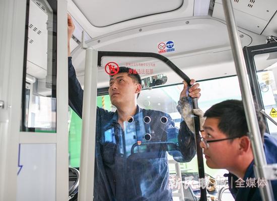 图说:工作人员正在为巴士三公司141路公交车安装防护隔离门 新民晚报记者 陈梦泽 摄(下同)