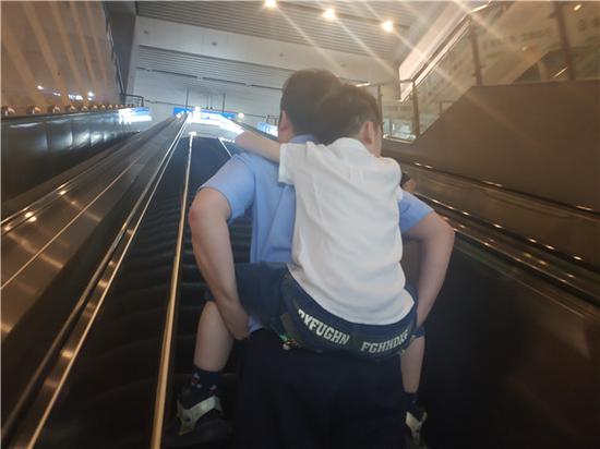 图说:民警刘宇翔背着沉睡的男孩上车,连夜冒雨将其送至户籍地派出所代为照顾。罗鹏飞 摄(下同)