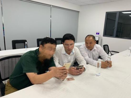 在工作人员见证下,余师傅(右一)给乘客许先生(左一)转回余款。 澎湃新闻记者 朱奕奕 图